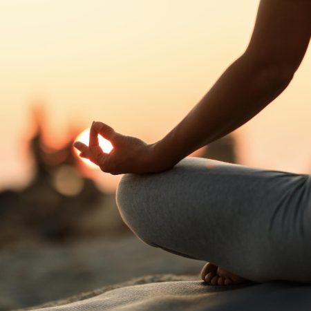 close-up-woman-meditating-lotus-position-sunset