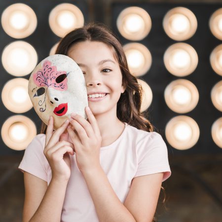 smiling-girl-holding-venetian-mask-her-hands-standing-front-stage-light